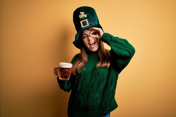 Sticker - Young beautiful woman wearing green hat drinking jar of beer on saint patricks day celebration with happy face smiling doing ok sign with hand on eye looking through fingers