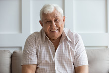Headshot Portrait Of Smiling Mature Man Relaxing On Sofa