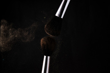 flying cloud of powder after the collision of two makeup brushes on a black background