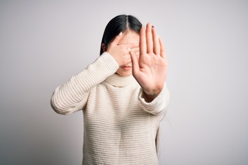 Sticker - Young beautiful asian woman wearing casual sweater standing over isolated background covering eyes with hands and doing stop gesture with sad and fear expression. Embarrassed and negative concept.