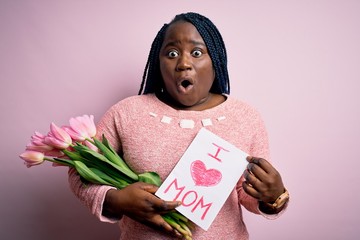 Wall Mural - Plus size african american woman holding love mom message and tulips on mothers day scared in shock with a surprise face, afraid and excited with fear expression