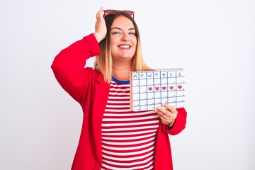 Sticker - Young beautiful woman holding period calendar standing over isolated white background stressed with hand on head, shocked with shame and surprise face, angry and frustrated. Fear and upset