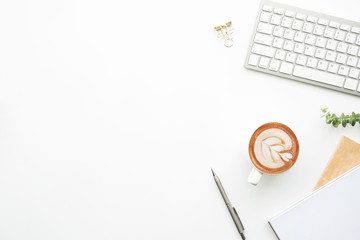 Minimal modern office desk table with computer keyboard, cup of coffee and supplies. Top view with copy space, flat lay.