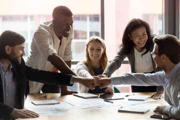 Poster - Happy diverse employees team joining fists, celebrating success