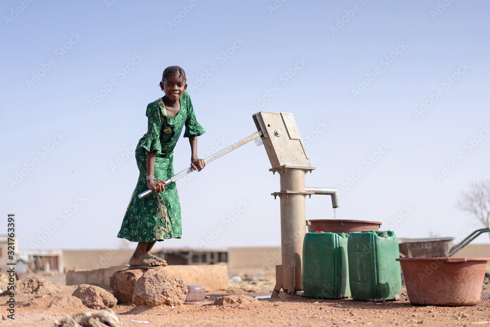 Happy Aboriginal Young Girl with lots of Water in a village - obrazy, fototapety, plakaty 