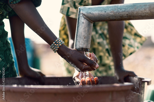 Plakat Happy African Girl Collecting Healthy Water with major difficulties