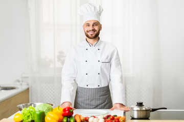 Male Chef In Uniform Smiling Standing In Kitchen