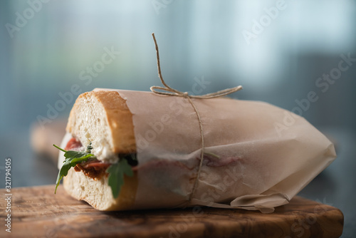 Cuadros en Lienzo Ciabatta sandwich with salame, arugula, red pesto and cream cheese wrapped in pa