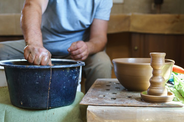 Clay candlestick on background of working potter.