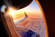 plane wing from airplane window seat in flight nature landscape against scenic sunset sky background. Aerial view from aircraft passenger cabin on beautiful red orange sunrise cloudscape and blue sky