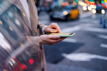 Wall Mural - Closeup photo of female hands with smartphone. Night street on background