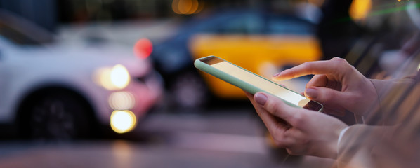 Wall Mural - Closeup photo of female hands with smartphone. Night street on background