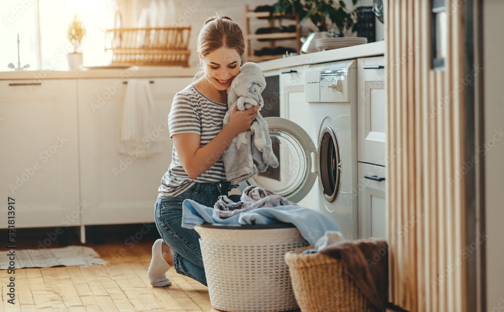 Happy housewife woman in laundry room with washing machine  . - obrazy, fototapety, plakaty 
