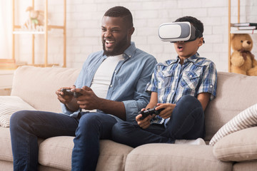 Wall Mural - Afro Father And Son Trying VR Glasses At Home, Playing Videogames