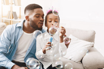 Wall Mural - Play together. Afro father and daughter blowing soap bubbles