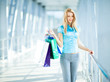© YouraPechkin - Beautiful women with smooth blonde hair posing while standing in shopping mall and holding shopping bags in hands. Photo with blurred background