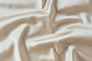 Golden light silk background with a folds.  Abstract texture of rippled satin surface