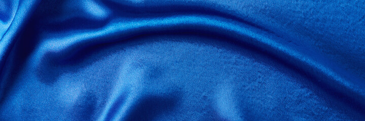 Blue silk background with a folds.  Abstract texture of rippled satin surface, long banner