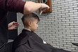  Caucasian boy getting hairstyle by hairdresser in barbershop.