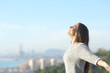 Woman breaths fresh air with a city in the background