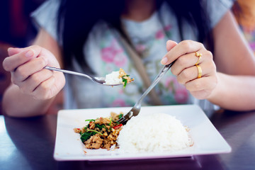 Asian woman eating hot steamed rice with a spoon in a white dish.at finger have 2 rings