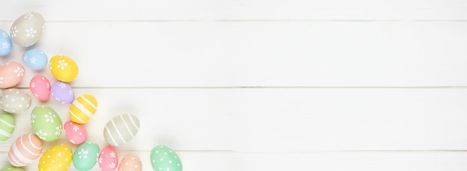 Pastel colored Easter Egg banner with corner border against a white wood background. Overhead view with copy space.