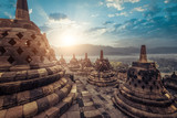Fototapeta Sawanna - Amazing view of stone stupas at ancient Borobudur Buddhist temple against beautiful landscape on background. Great religious architecture. Magelang, Central Java, Indonesia
