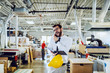 © Dusan Petkovic - Positive Caucasian bearded director reading notes from notebook and talking on the phone while standing in printing shop. In background are printing machines.