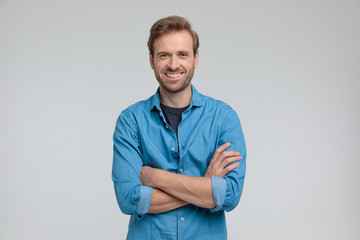 Wall Mural - enthusiastic young casual man crossing arms and smiling