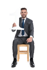 Wall Mural - young businessman holding number one sign and smiling