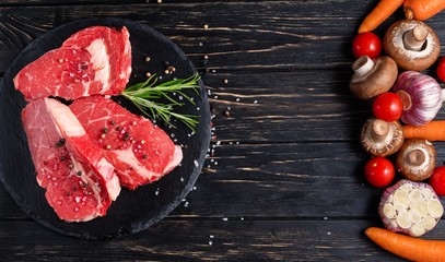 Wall Mural - On one side of the table are vegetables on the other side of a beautiful juicy, raw beef meat. Choose your food.