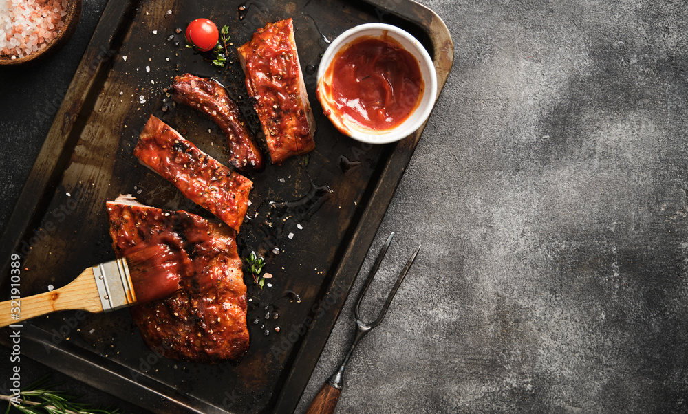 Delicious barbecued ribs seasoned with a spicy basting sauce and served on iron pan. - obrazy, fototapety, plakaty 