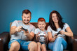 © Aliaksandr Marko - A cheerful family, dad mom and son play on the console, video games, emotionally react sitting on the couch. Day off, entertainment, leisure, spend time together.