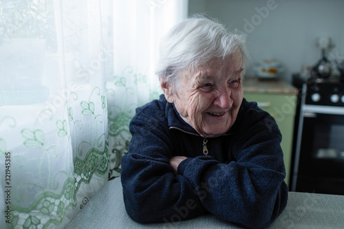 Fotografía An old woman pensioner laughs sitting at the table.