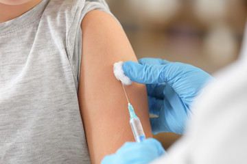 doctor vaccinating little girl in clinic, closeup