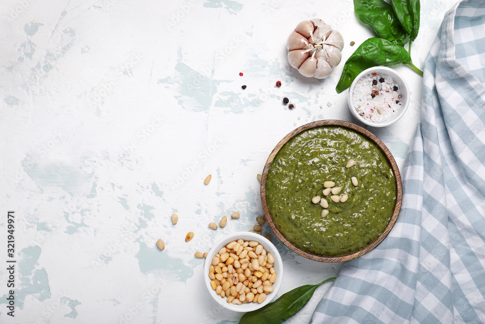 Bowl with pesto sauce and ingredients on white background