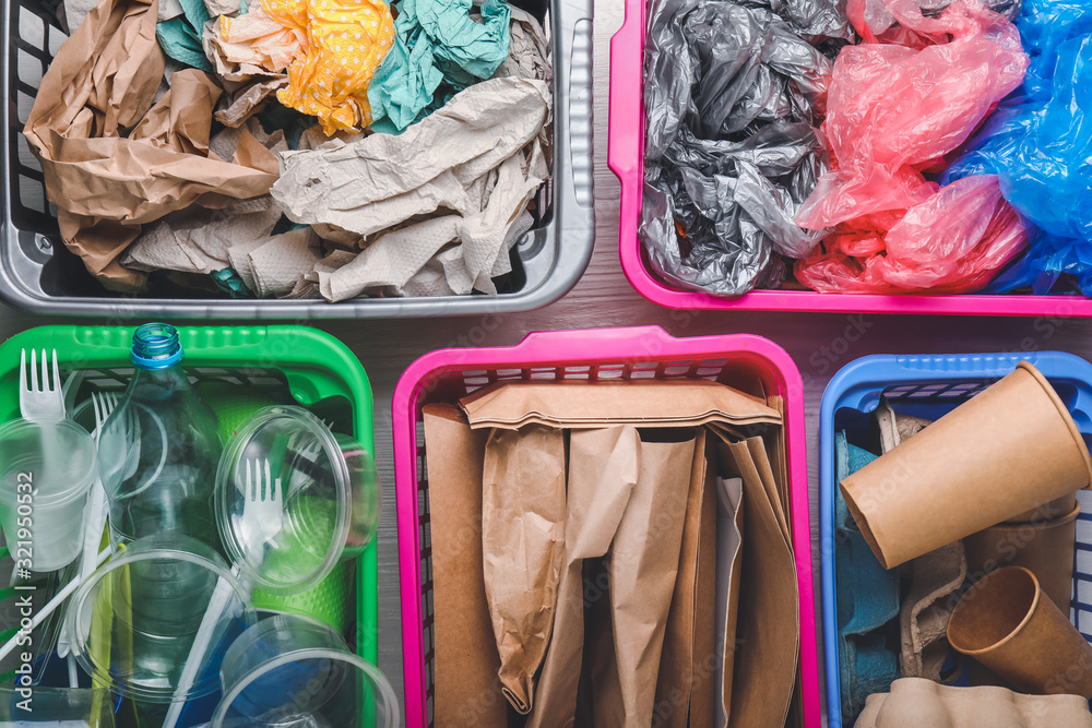 Baskets with different garbage on table, top view. Concept of recycling