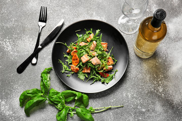 Plate with tasty salmon salad and wine on grey background