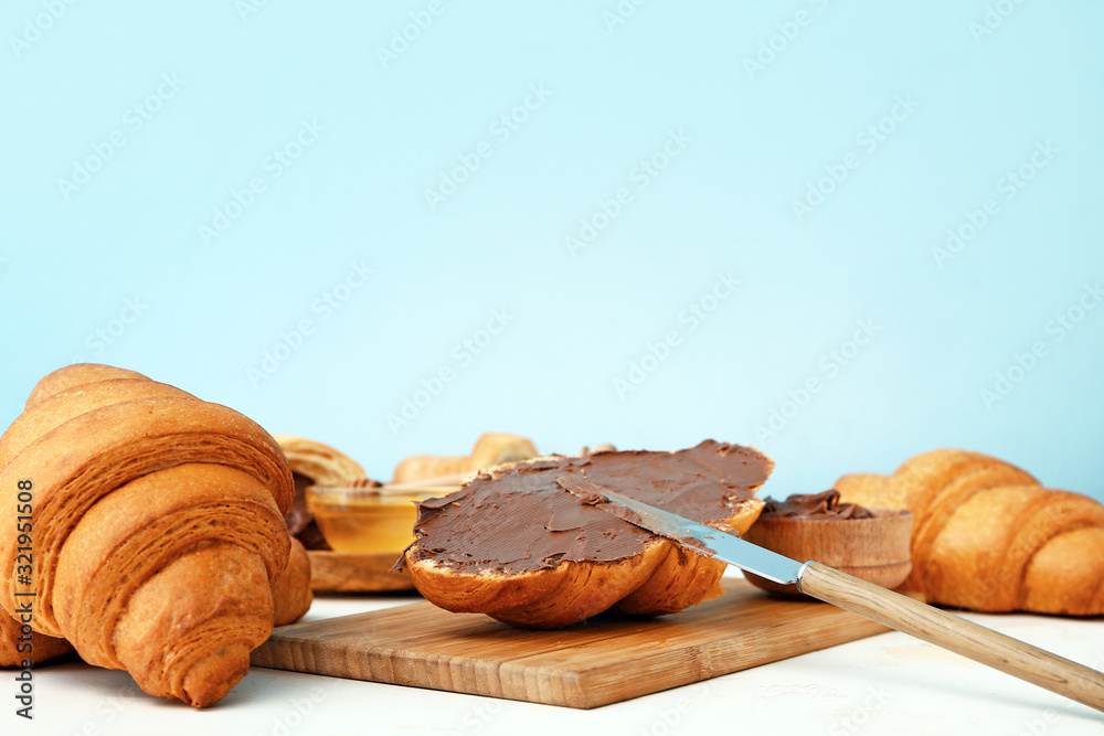 Tasty sweet croissants with chocolate on color background