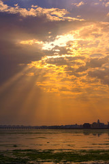 Wall Mural - Sunlight shine thru colorful clouds with flares on the beach sea view background, Bahrain.