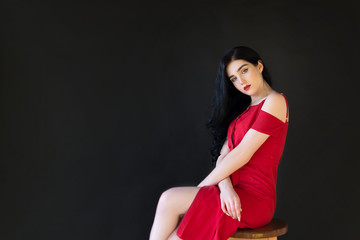 beautiful girl sits on a chair, on a black background