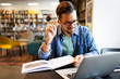 © NDABCREATIVITY - Young man student with laptop studying in the university library
