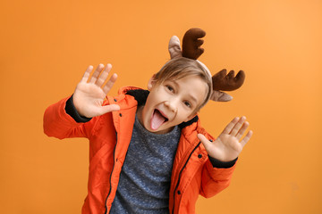 Wall Mural - Funny little boy with deer horns on color background