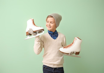 Wall Mural - Cute little boy with ice skates against color background