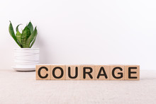 Courage Word Written On Wooden Blocks On A Light Table With A Flower And Light Background