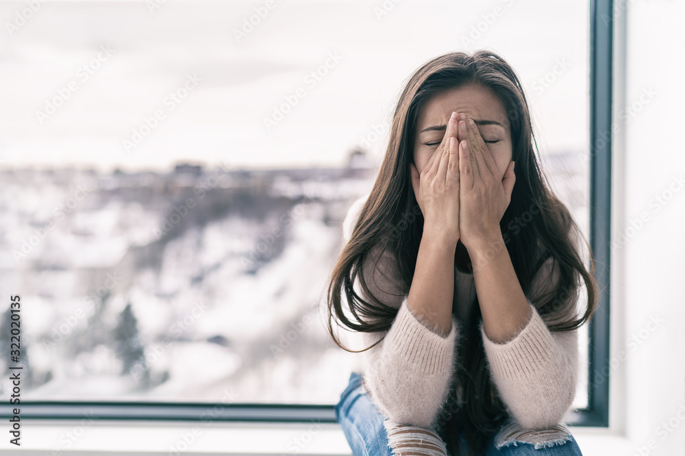 Depressed woman in shock or grief crying at home alone feeling sad with winter blues seasonal affective disorder. Mental health concept. - obrazy, fototapety, plakaty 