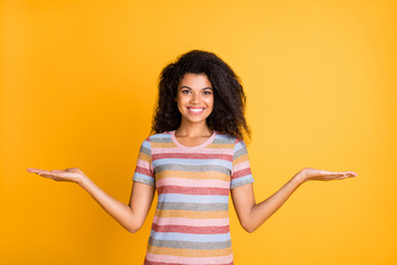 Wall Mural - Portrait of her she nice attractive cheerful cheery wavy-haired girl wearing striped tshirt holding on palms two invisible objects isolated on bright vivid shine vibrant yellow color background