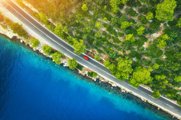 Wall Mural - aerial view of road in beautiful green forest and sea coast at sunset in spring. colorful landscape 