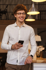 Poster - Smiling young man using mobile phone while standing