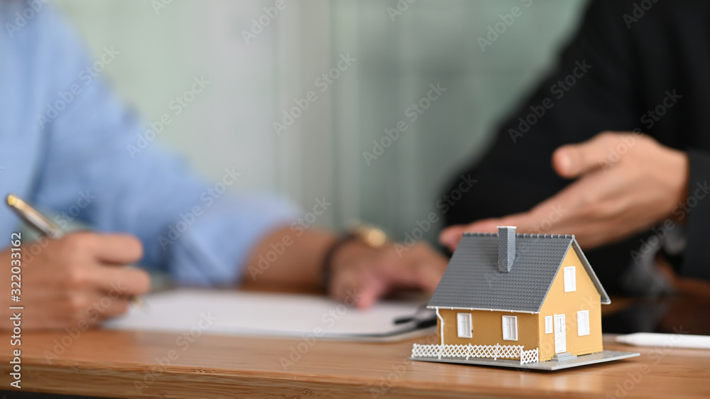 Cropped shot of Real estate agent offer house insurance or house ownership to smart man in blue shirt at the modern wooden table. Signing on agreement, Broker/Seller/Dealer concept. - obrazy, fototapety, plakaty 